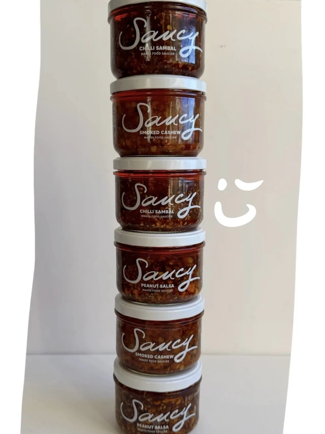 The Extra Saucy Collection (Set Of 6), a collection of 6 sauces sitting on a white table surface against a grey backdrop. 