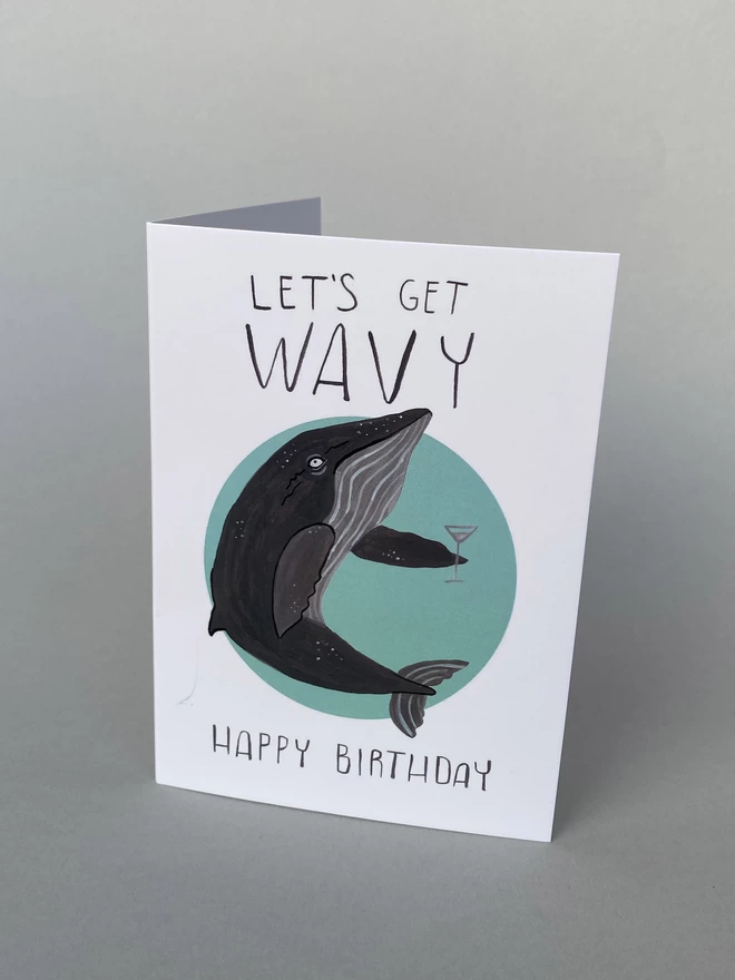 Illustrated birthday card with a whale holding a drink that reads - Lets get Wavy, Happy Birthday