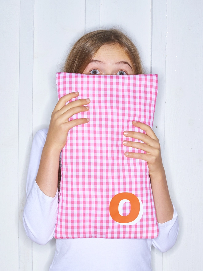 Personalised pink gingham hot water bottle with 3D initial in orange with white highlight