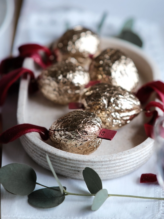 Handmade walnut Christmas ornament with delicate gold gilding, showing the natural shape and grain of the wood. A traditional, nostalgic Christmas tree decoration with timeless old-fashioned charm.