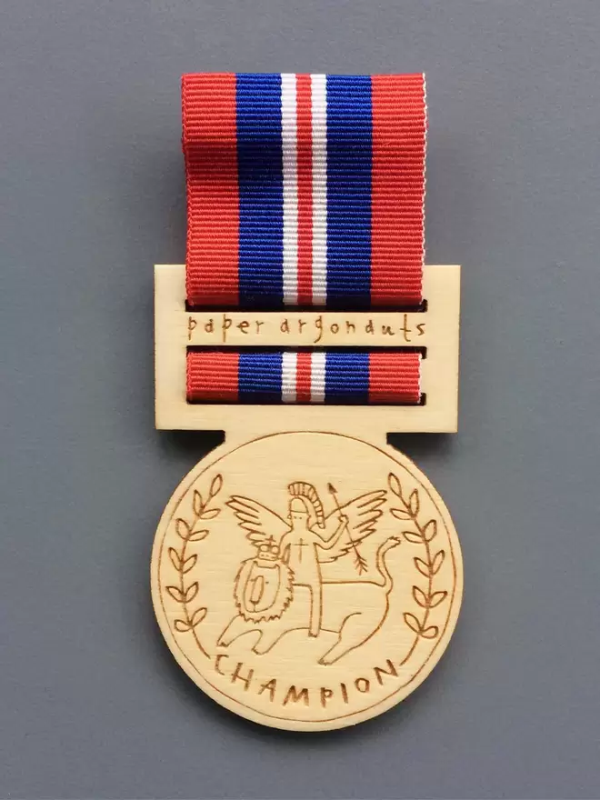 'Champion' medal pin badge, a brave winged hero rides a lion. Hung on red, white and blue ribbon