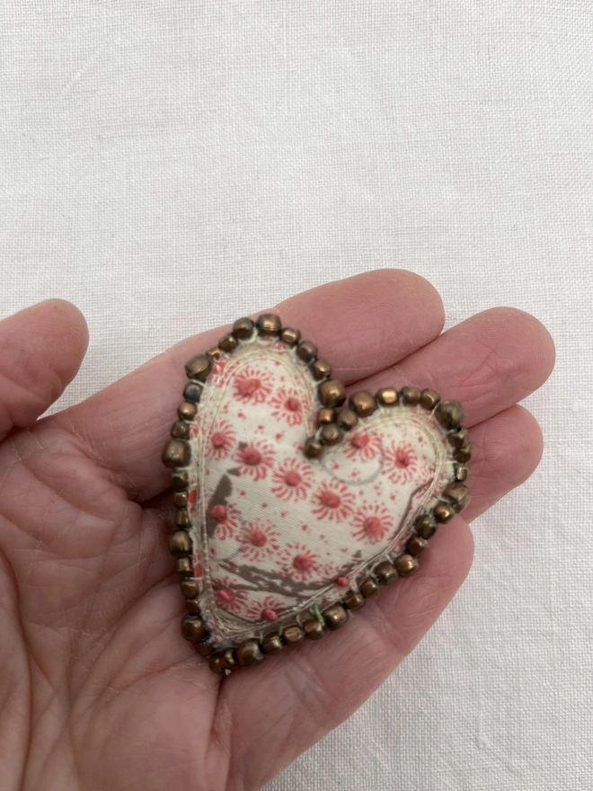 bronze beaded brooch on hand