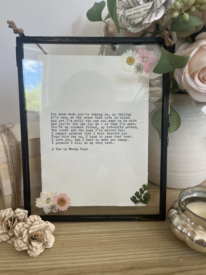 Framed typewriter print hand typed with an antique typewriter onto cotton rag handmade deckled paper. It is displayed in a black hanging rustic frame with gold brush detailing and decorated with real pressed dried flowers.