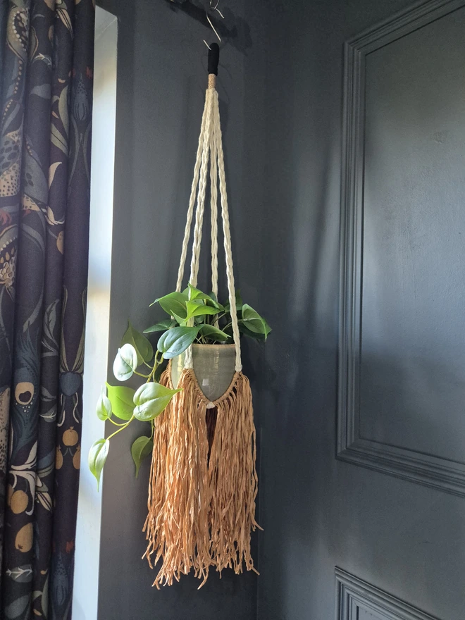 Handmade boho raffia paper plant hanger, adding texture and warmth to any space with a unique raffia fringe. stylish and modern hanging planter, perfect for indoor greenery and home decor trends