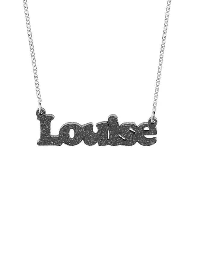 Personalised Name Neckace from Tatty Devine. The Necklace is the word Louise laser cut from Deluxe Black Glitter Acrylic on a silver-plated chain.
