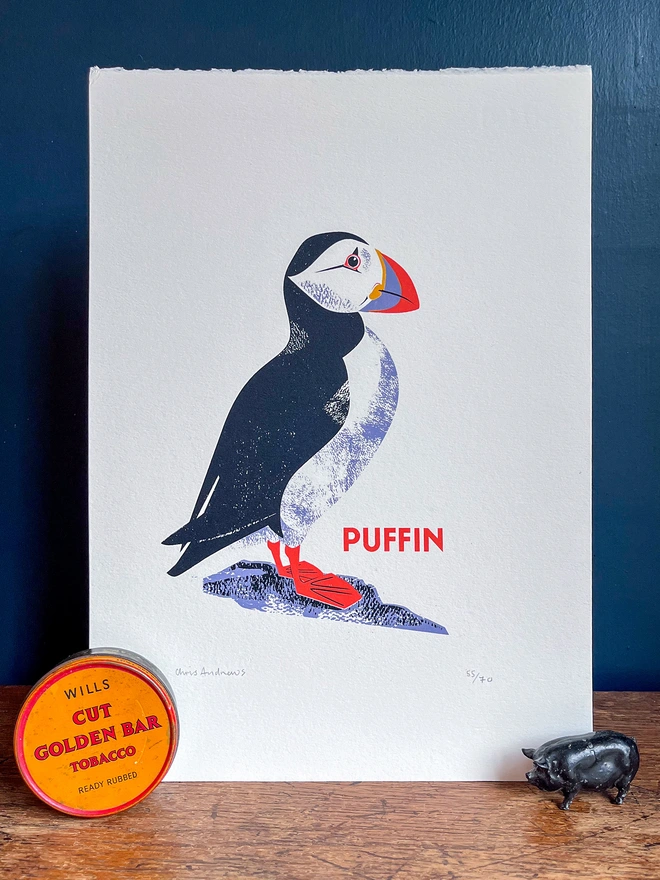 A screenprint of a Puffin on white paper against a navy blue background.