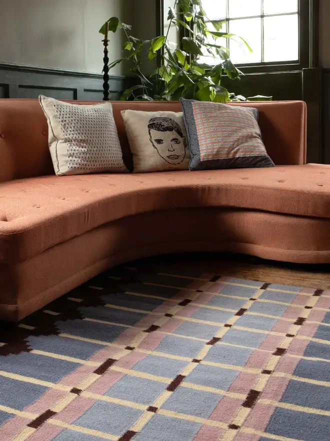 Corbie Flatweave Rug, a colourful rug sitting in a decorated room. It is accompanied by other household items. 