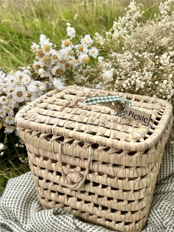 woven picnic basket with a ceramic tag tied to the handle with green gingham ribbon. Tag reads 'picnic'.