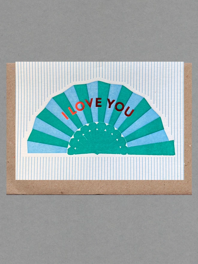 White card with blue and green fan with red text reading 'I Love You' on green and white striped card with a brown envelope behind
