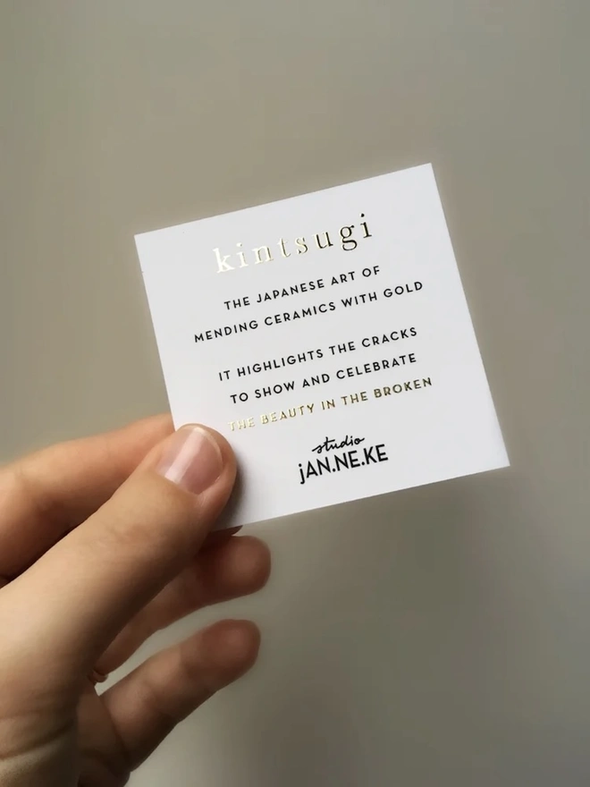 (Un)Broken Heart Pin, a black box with a card explaining the white and gold heart pin. 
