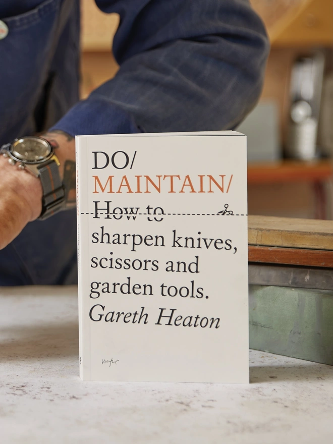 Book standing up on work surface next to pile of whetstones
