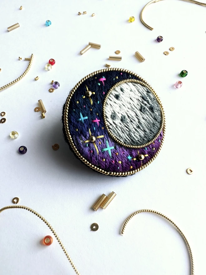 Cosmic Moon brooch on background with beads