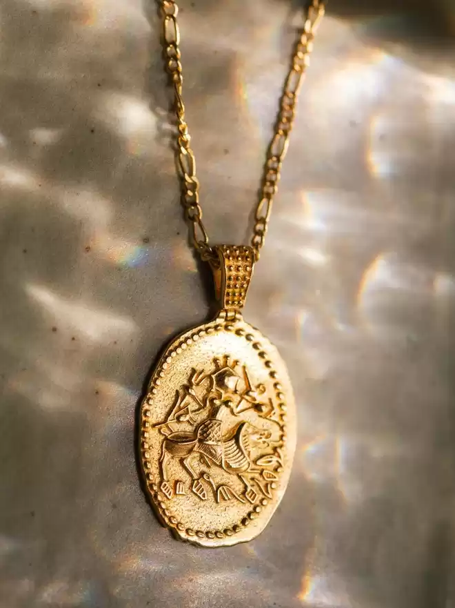 Gold vermeil oval coin pendant featuring the Hindu goddess Durga on shiny backdrop
