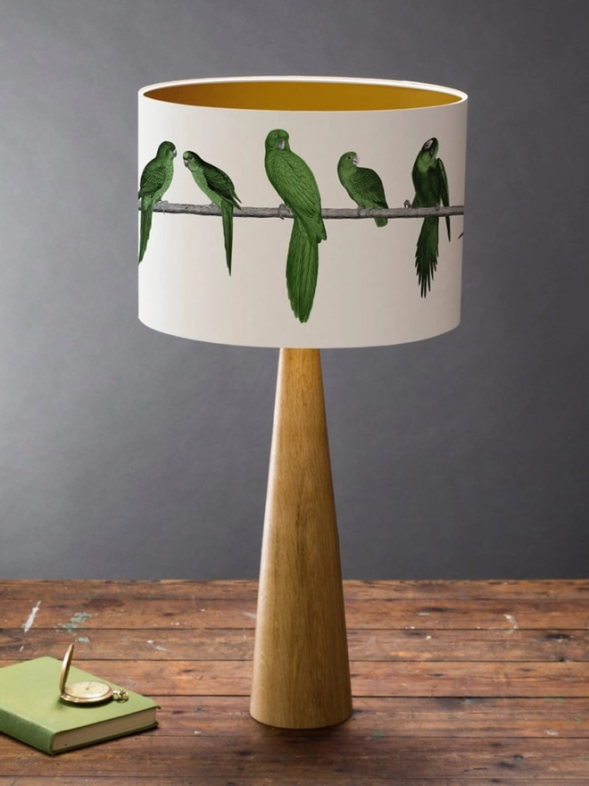 A colourful lampshade featuring a lively group of green parrots in a tropical jungle-inspired design, bringing a playful touch to home interiors.