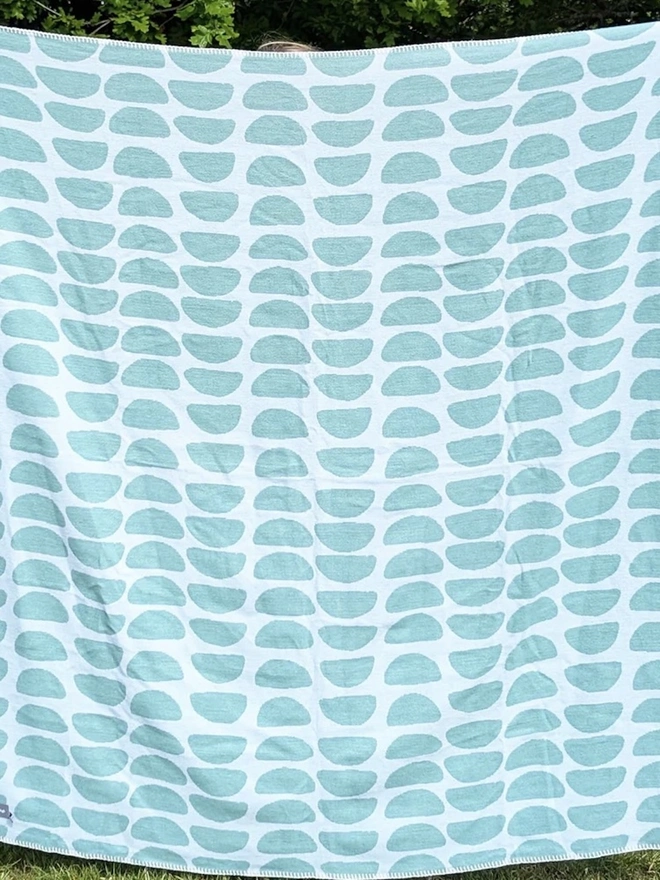 Organic Cotton Throw, a person holding the throw in front of them outside. 