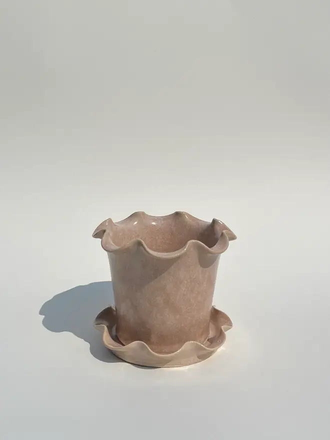 Frilly Plant Pot And Saucer, a collection of colourful plant pots sitting on a plain surface. 