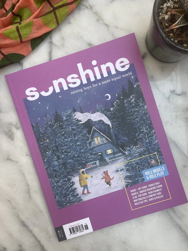 Sonshine magazine issue 18 a purple mag with an illuatrain of an adult and child playing outside in a snowy landscape infront of a cosy wooden house