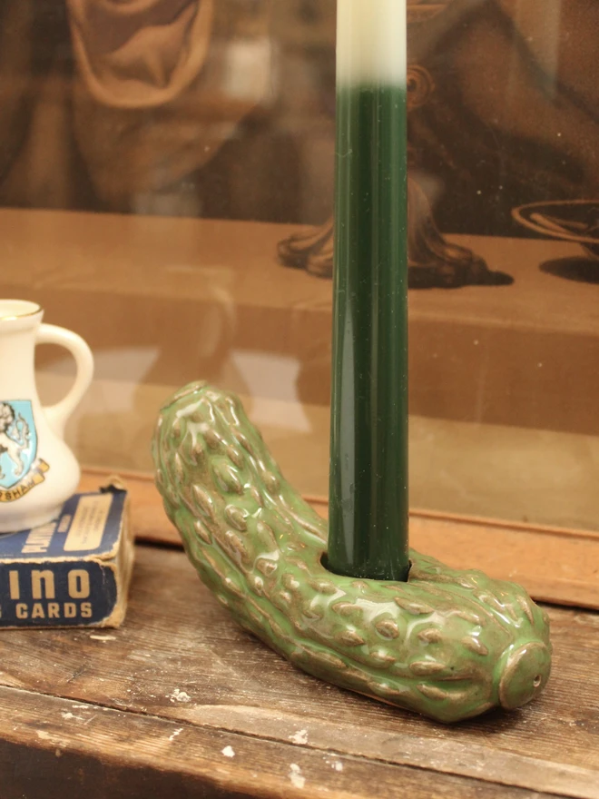 Pickle Candle Holder, a pickle candle holder sitting on a wooden surface with a candle in it. 