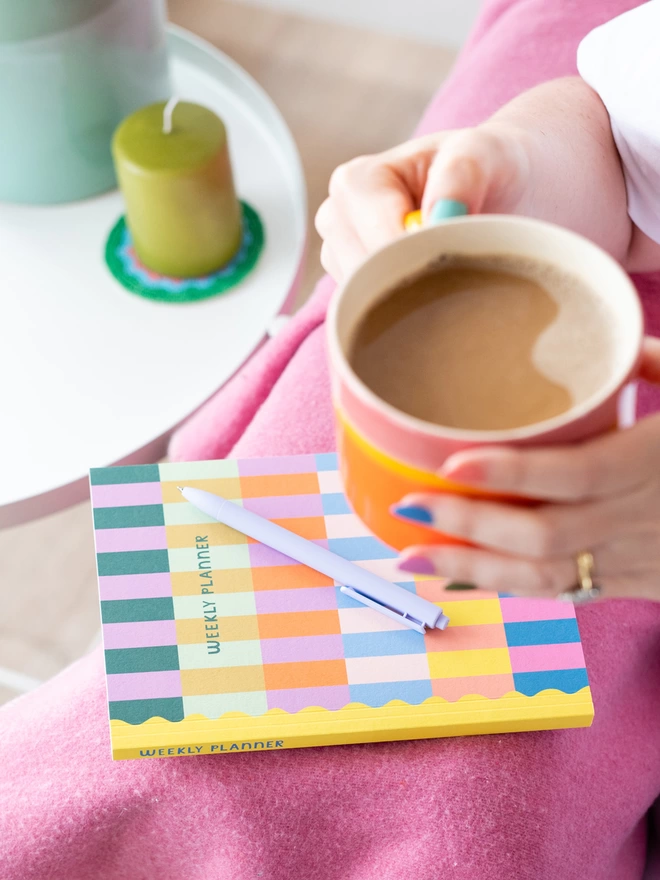 Woman enjoys a coffee with her vibrant rainbow Raspberry Blossom weekly planner
