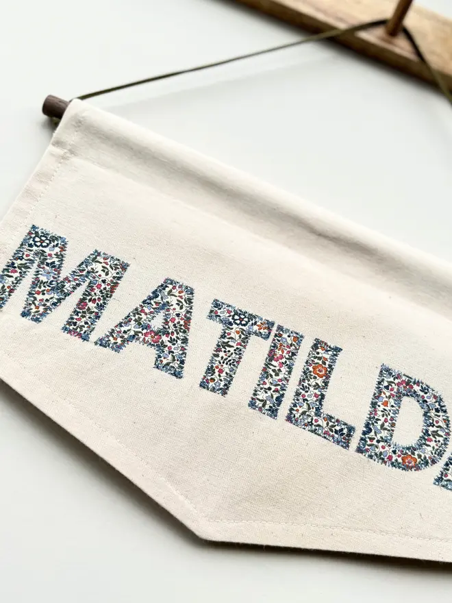 Personalised Name Banner. A banner hung with the word MATILDA in blue and pink floral letters