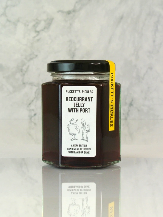 redcurrant jelly with port. a jar of redcurrant jelly photographed on a marble background. 