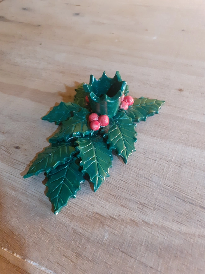 Artisan ceramic holly leaf candle holder without candle, showing the layered leaf detail and shiny glaze finish in festive green and red tones.