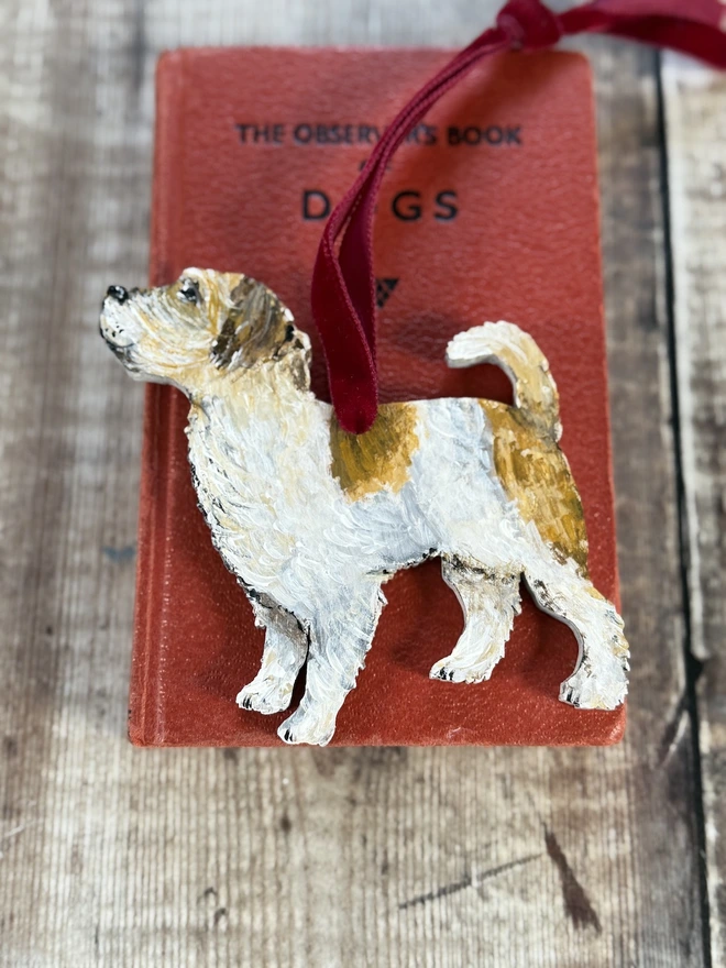 Wire Haired Jack Russell Christmas decoration strung with red velvet and placed on a red book 