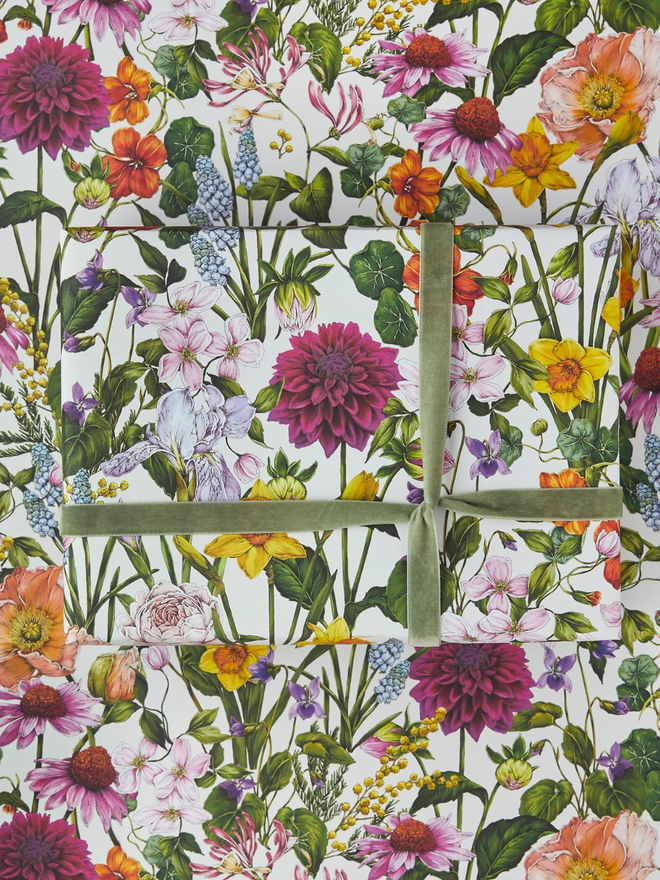 bountiful blooms floral gift wrap sheet. a box wrapped in multi-coloured illustrated floral gift wrap with a green ribbon.