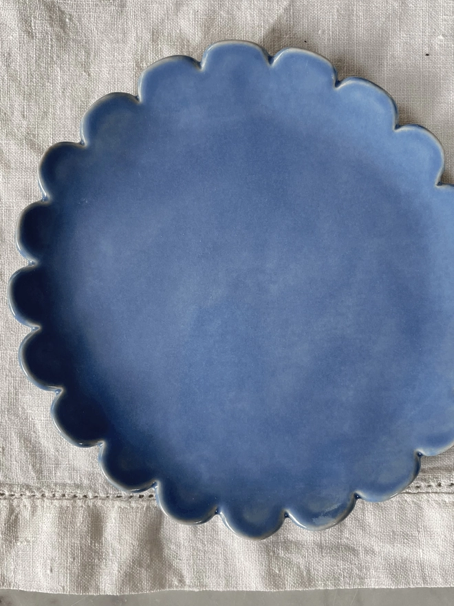 top view of camellia scalloped edge side plate in periwinkle blue
