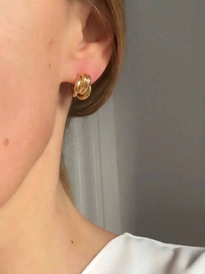 gold huggie earrings with a knotted design that curve comfortably around the earlobe