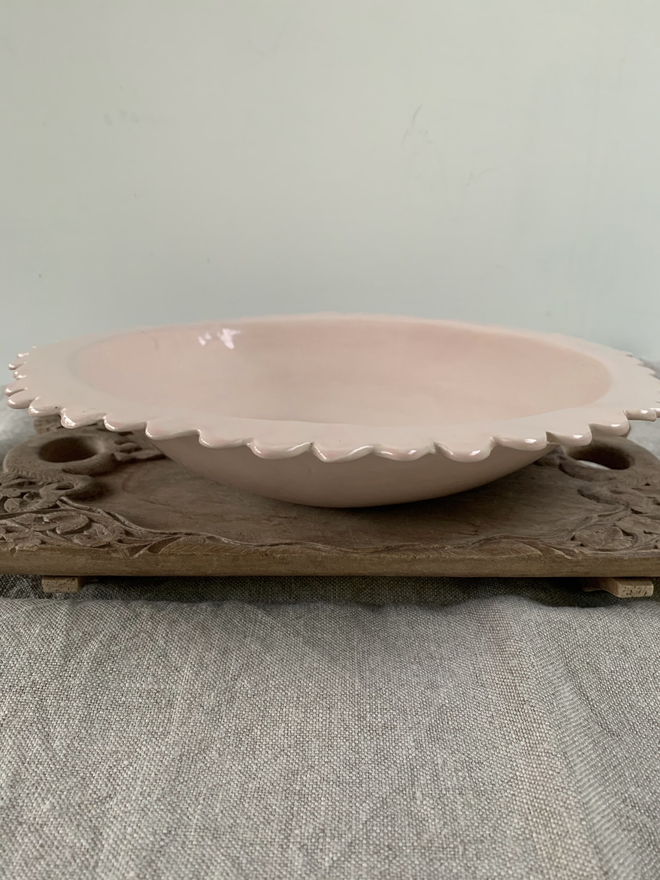 profile view of large scalloped edge serving bowl in pink