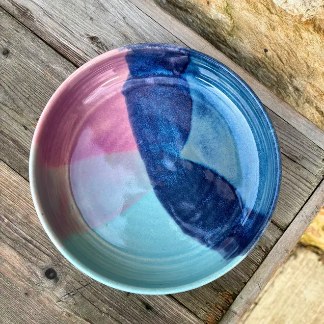 Landscape Pasta Bowl, a colourful pasta bowl on a wooden surface against a brick backdrop. 