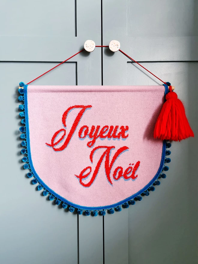 A Joyeux Noel banner hangs from a panelled wooden door.