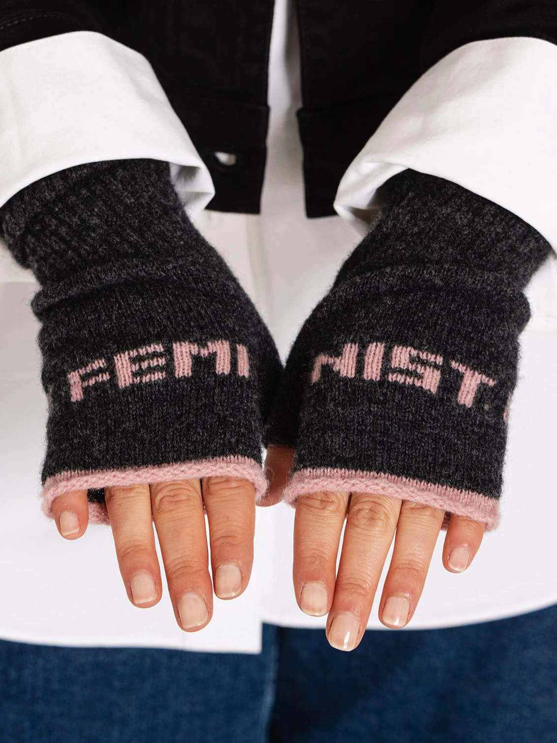 Charcoal feminist mittens with calamine pink trim on hands