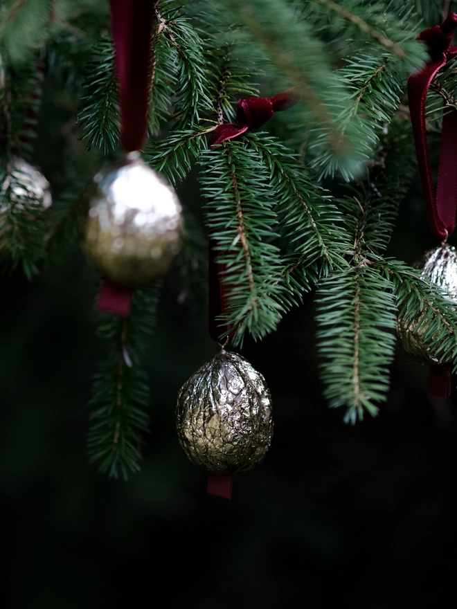 Handmade walnut Christmas ornament with delicate gold gilding, showing the natural shape and grain of the wood. A traditional, nostalgic Christmas tree decoration with timeless old-fashioned charm.