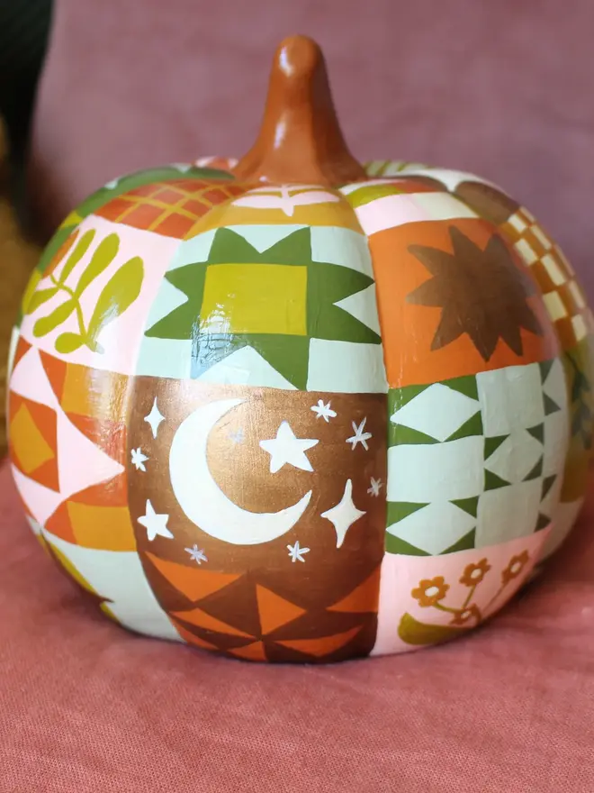 hand-painted woodland ceramic pumpkin. a ceramic pumpkin painted with patchwork colours and patters, alongside mushrooms, moons, stars and flowers.