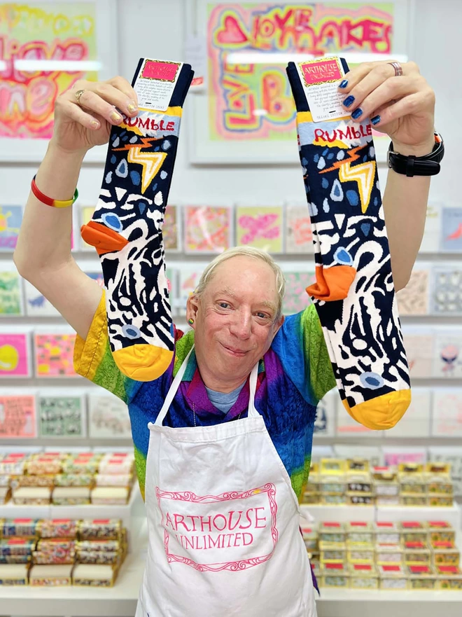 Happy artist holding 100% Organic charity cotton Rumble Socks in blue & yellow
