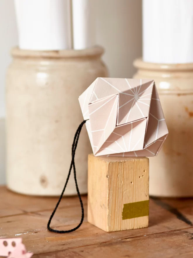 Paper diamond balanced on a wooden block.