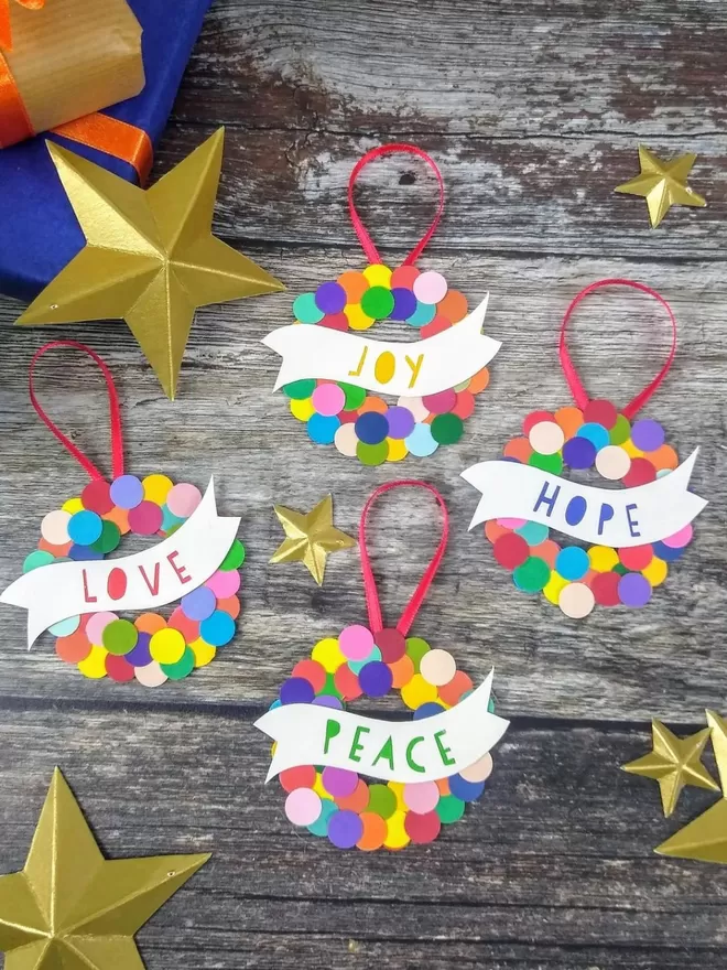 Colourful Christmas Baubles set of four. Wreath shaped bauble covered in mulitcoloured dots with a banner across the middle. Red hanging loop attached.