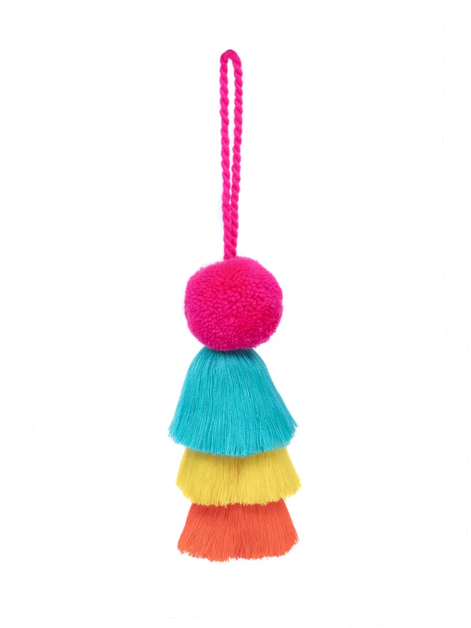 pom pom and tassel swag hanging decoration. a pink, blue, yellow and orange hanging decoration.