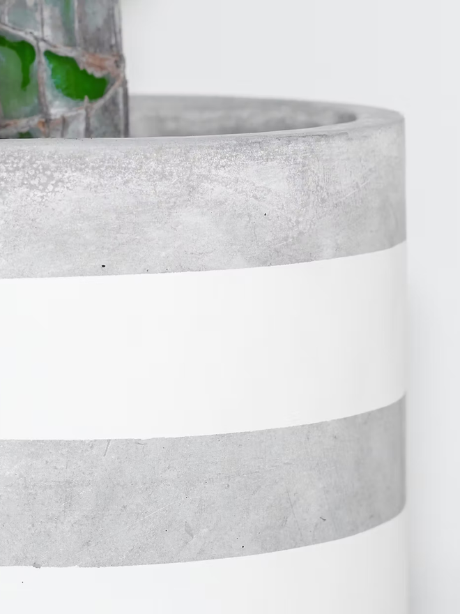 two stripes concrete plant pot. a grey plant pot with grey painted stripes.