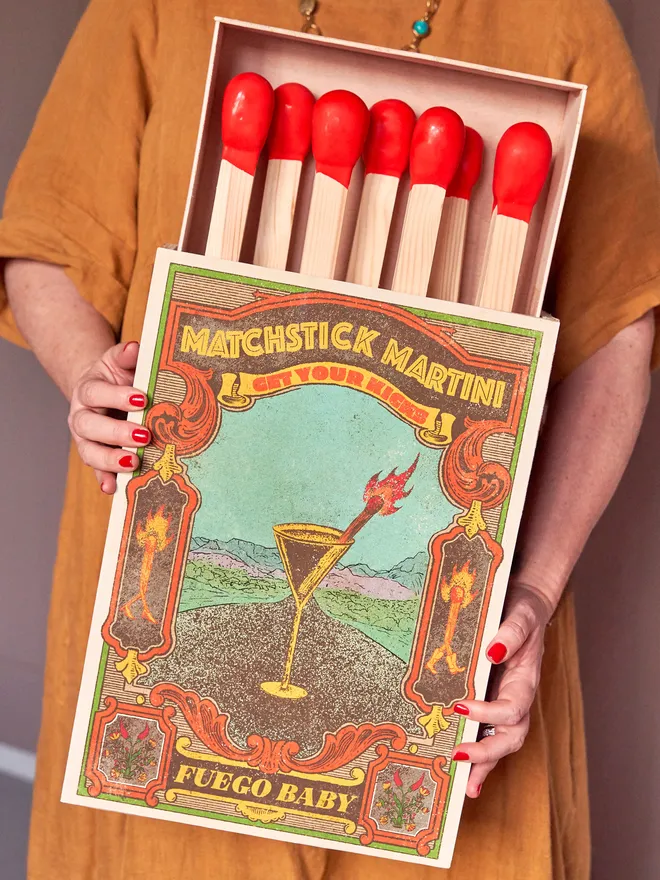 Personalised oversized matchbox. A large matchbox held by someone in an ochre dress