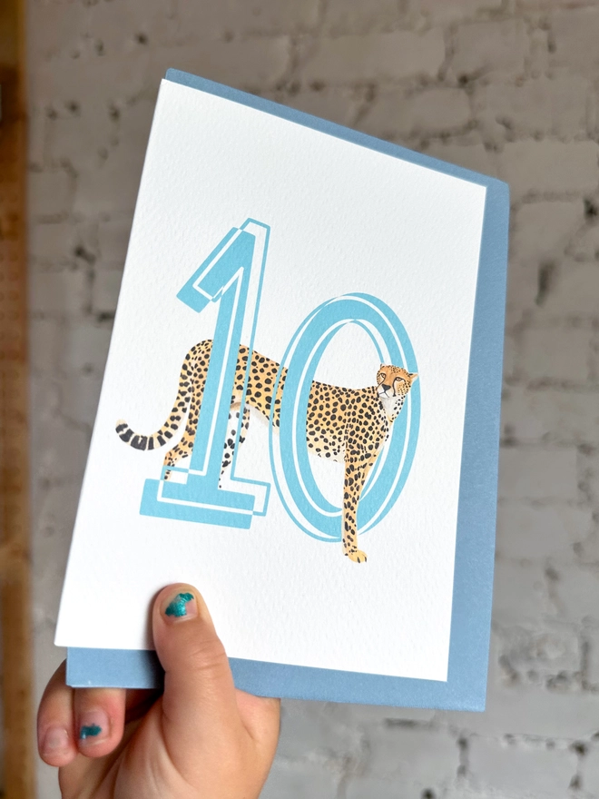 a white card with a big blue number 10 and an illustration of a cheetah with a pale blue envelope