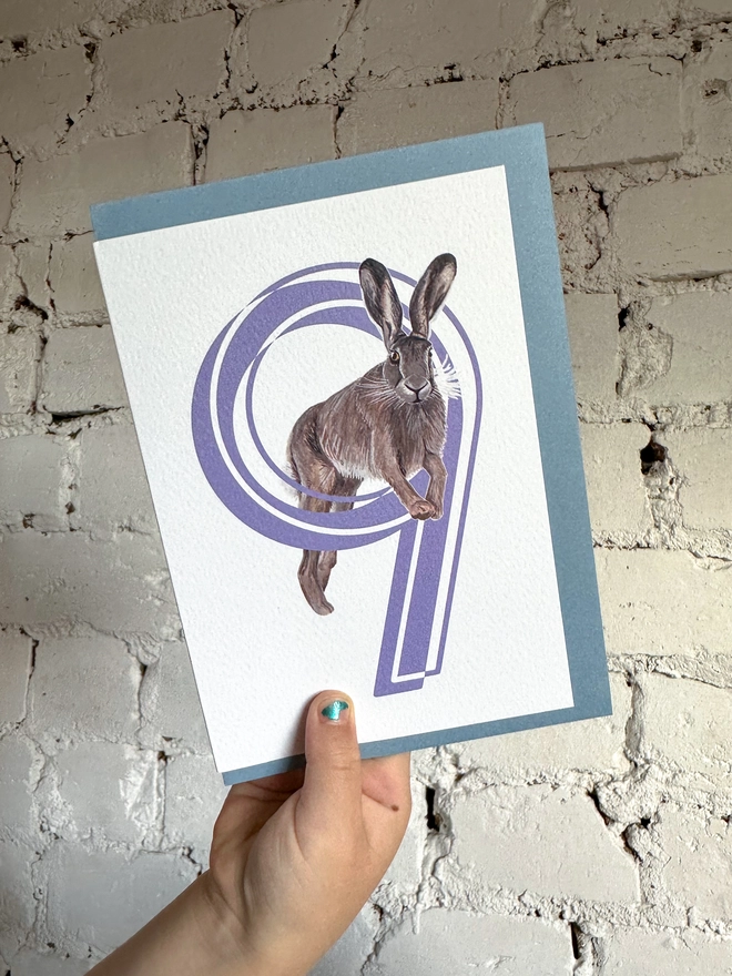white card with a big purple number 9 and a hare illustration with a blue envelope
