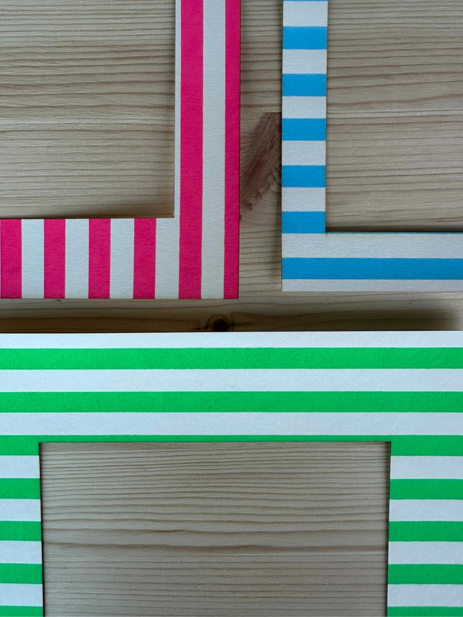 Thin Striped Screen Printed A6 / A5 / A4 Photo Mount. borders of pink, blue and green versions of striped mount shown on wooden surface.