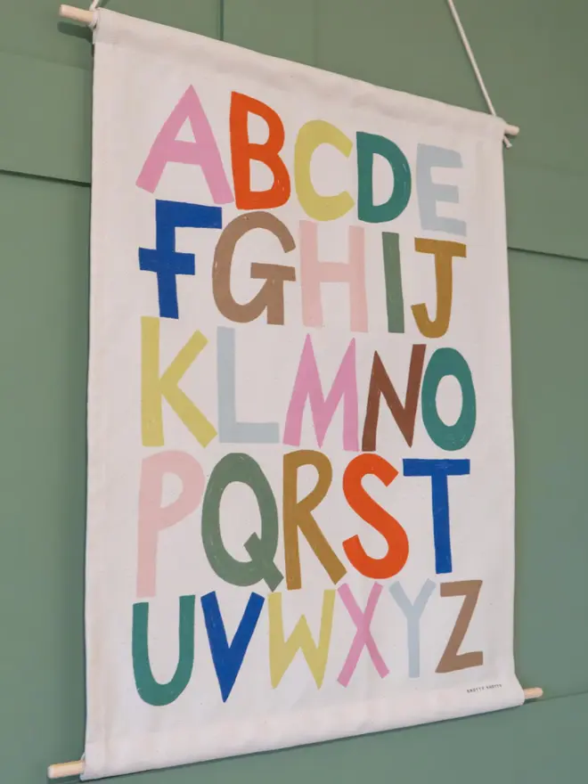 Rainbow Alphabet Fabric Banner, hanging on a green wall. 