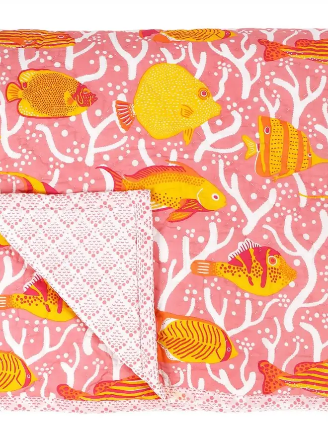 Pink Coral Reef Quilt, a pink quilt sitting on a white surface. 