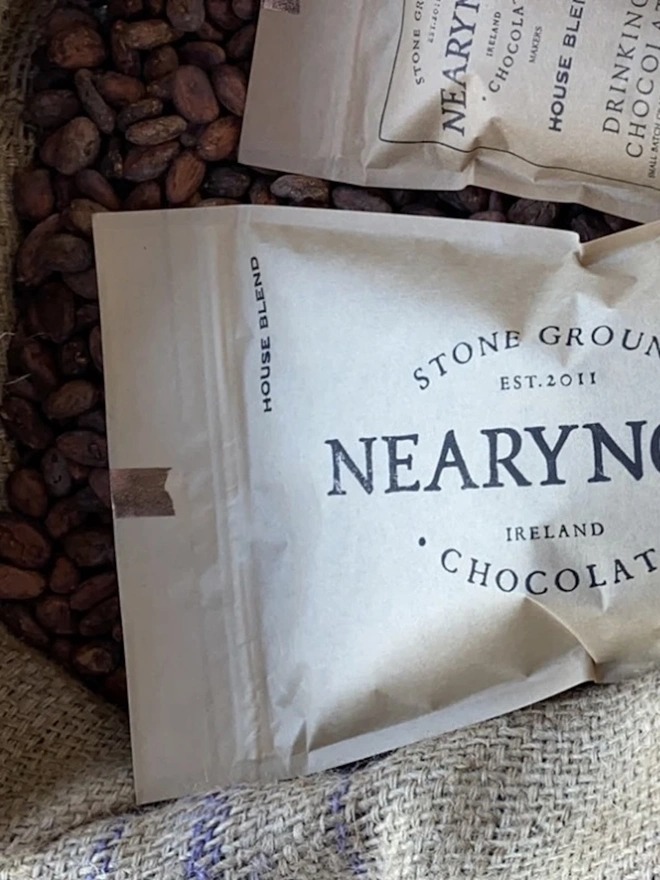 Drinking Chocolate 60% (Pack Of 200g/ 1kg), a packet of drinking chocolate sitting on a bag of nuts. 