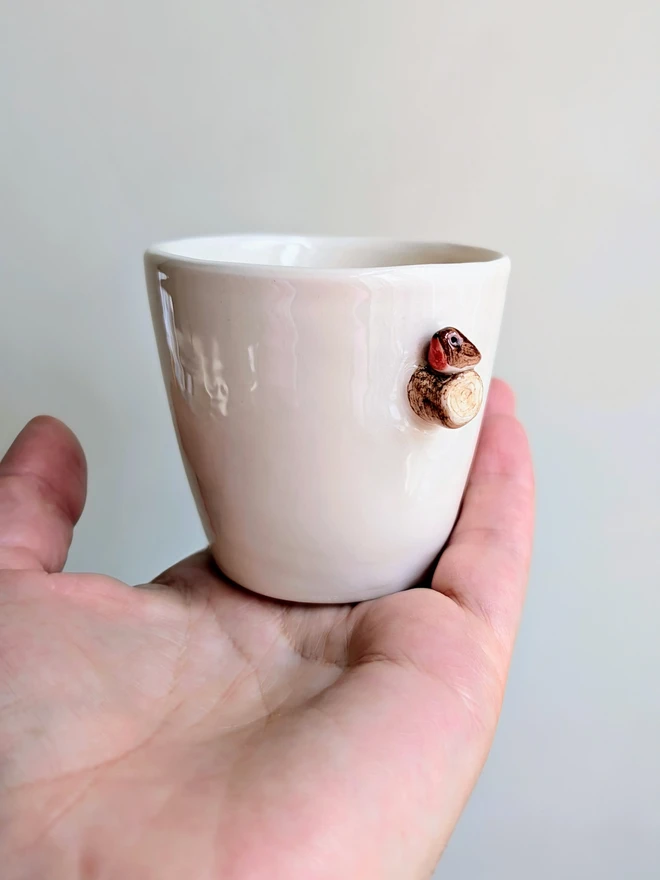white espresso coffee cup with tiny robin red breast bird on a ceramic tree branch