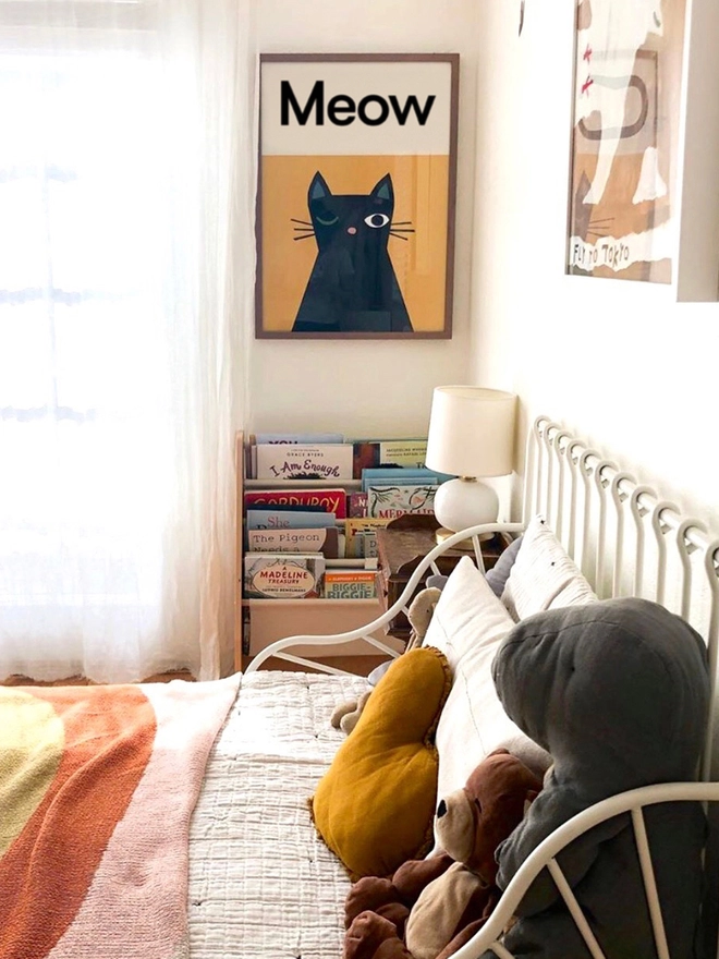 illustrated cat wall print hanging on a bedroom wall